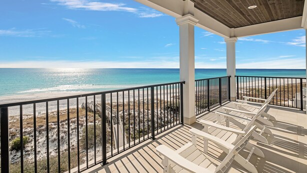 Un balcon fermé offrant une vue sur la plage et l’océan.