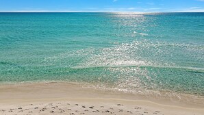 Une plage avec une eau turquoise cristalline et un rivage sablonneux.