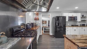 Een moderne keuken met roestvrijstalen apparatuur, een houten aanrecht en uitzicht op de eetruimte.
