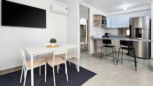 A modern kitchen with a built-in stove, a refrigerator, and a microwave. There is a dining area with a table and chairs, and a potted plant on the table. - Luxury & Calm in Serena del Mar: Your New Retreat at Capriella (cartagena)