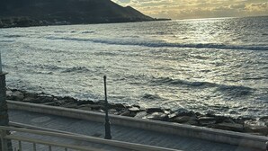 A coastal view with a railing, a rocky shoreline, and a distant mountain. - The window to the sea (Santa Maria di Castellabate)