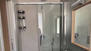 A modern bathroom with a glass-enclosed shower, a white sink, and a mirror above it. - Spinal (VICO DEL GARGANO)