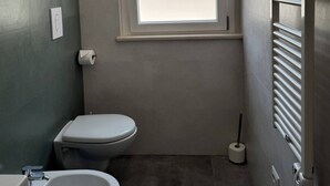 A small bathroom with a toilet, bidet, and a window providing natural light. - Spinal (VICO DEL GARGANO)