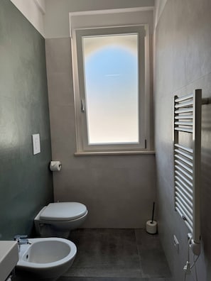 Ein kleines Badezimmer mit Toilette, Bidet und einem Fenster für natürliches Licht.