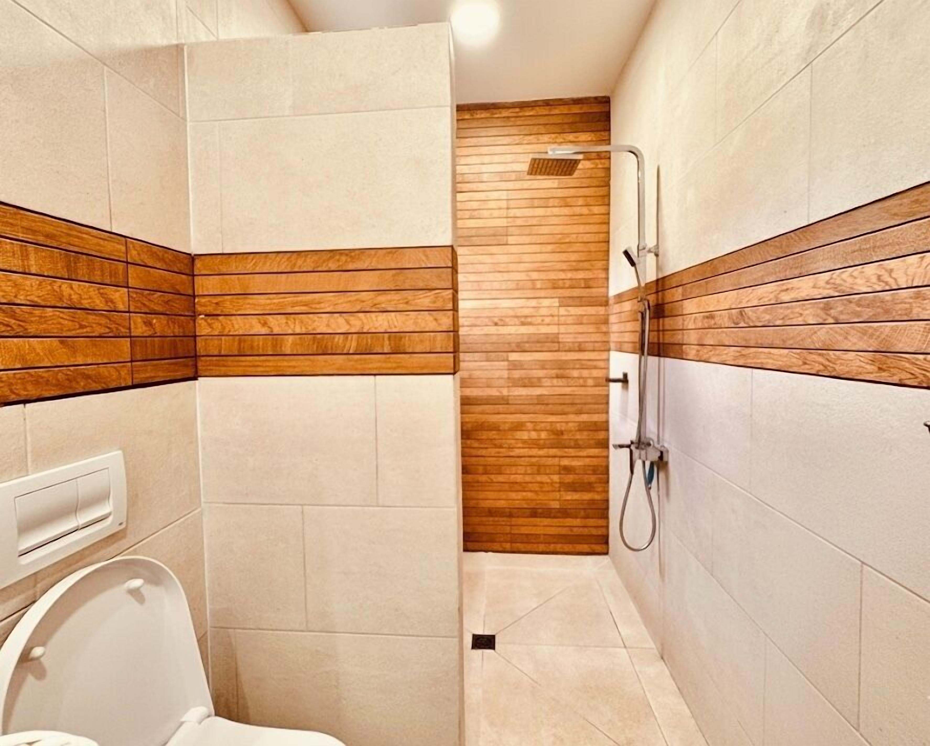 Un baño moderno con ducha, inodoro y una pared de acento de madera.