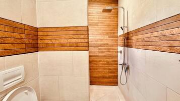 Un baño moderno con ducha, inodoro y una pared de acento de madera.