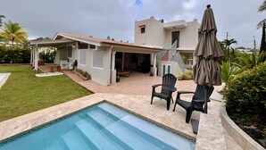 Uma casa com piscina, área de estar ao ar livre e varanda coberta.