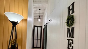 Um corredor com uma luminária, uma porta e uma parede com a palavra 'HOME'.