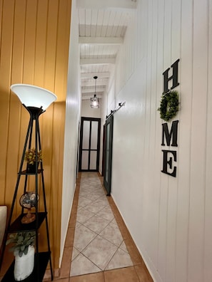 A hallway with a lamp, a door, and a wall with 'HOME' letters. - Relaxing 5BR Country Getaway w/ Heated Pool · Perfect for Groups (Cidra)