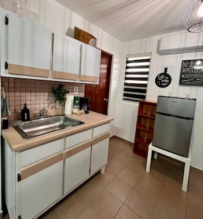 A compact kitchen with white cabinets, a stainless steel sink, a coffee machine, and a refrigerator. - Relaxing 5BR Country Getaway w/ Heated Pool · Perfect for Groups (Cidra)