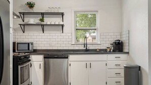 Eine moderne Küche mit weißen Schränken, einem Edelstahl-Geschirrspüler, einer Mikrowelle und einer Kaffeemaschine.