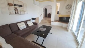 A living room with a sofa, coffee table, and a fireplace. There is a staircase leading to another room. - VILLA LE CLOS BUCCI WITH PRIVATE POOL AND SUPERB SEA VIEW LES HAUTS DE GRIMAUD (Grimaud)