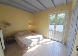 Ein Schlafzimmer mit einem Bett, einem Nachttisch, einer Lampe und einer Schiebetür zu einem Außenbereich.