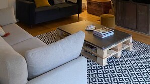 Una sala de estar con sofá, mesa de centro, lámpara, chimenea y un cuadro en la pared.
