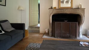 Una sala de estar con chimenea, un sofá, una lámpara y un cuadro en la pared.