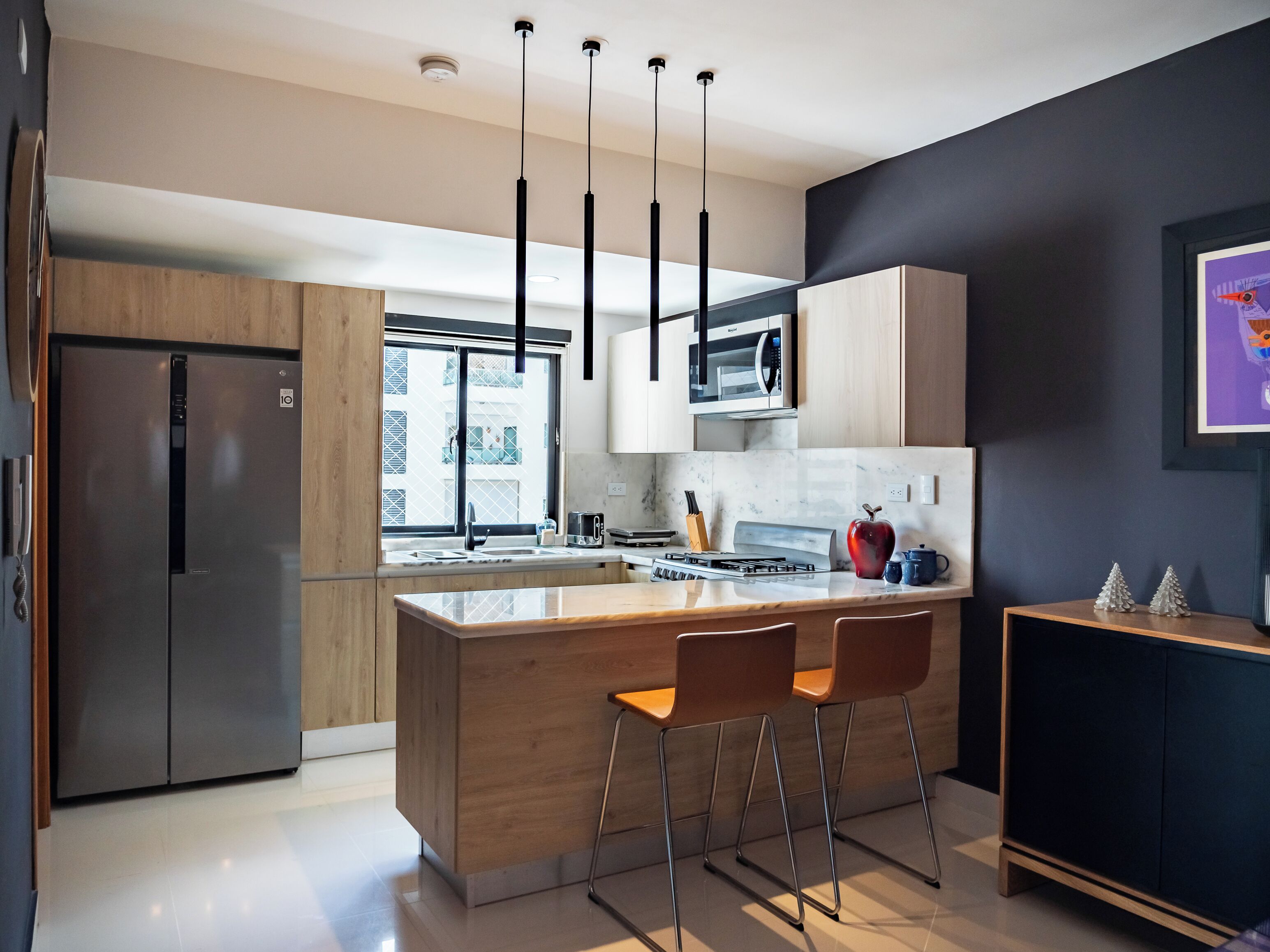 A modern kitchen with a central island, stainless steel appliances, and a dark accent wall.