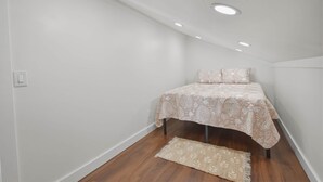 Ein Schlafzimmer mit einem Bett, einem Teppich und Einbaustrahlern.