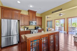 A modern kitchen with wooden cabinets, stainless steel appliances, and a large island. - Magnolia Breeze Getaway - Steinhatchee Florida (Steinhatchee)