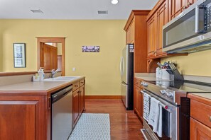 A kitchen with wooden cabinets, a stainless steel refrigerator, a microwave, and an oven. - Magnolia Breeze Getaway - Steinhatchee Florida (Steinhatchee)