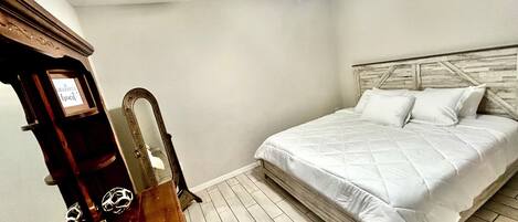 A bedroom with a bed, a ceiling fan, a wooden headboard, and a wooden dresser with a mirror.