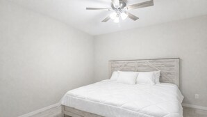A bedroom with a wooden headboard, a white bedspread, and a ceiling fan. - Perfect 4-bedroom house with AC in peaceful Port Charlotte (Port Charlotte)