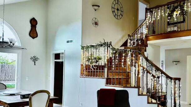 Un salón amplio con una escalera de madera, una mesa de comedor y un conjunto de asientos acogedor.