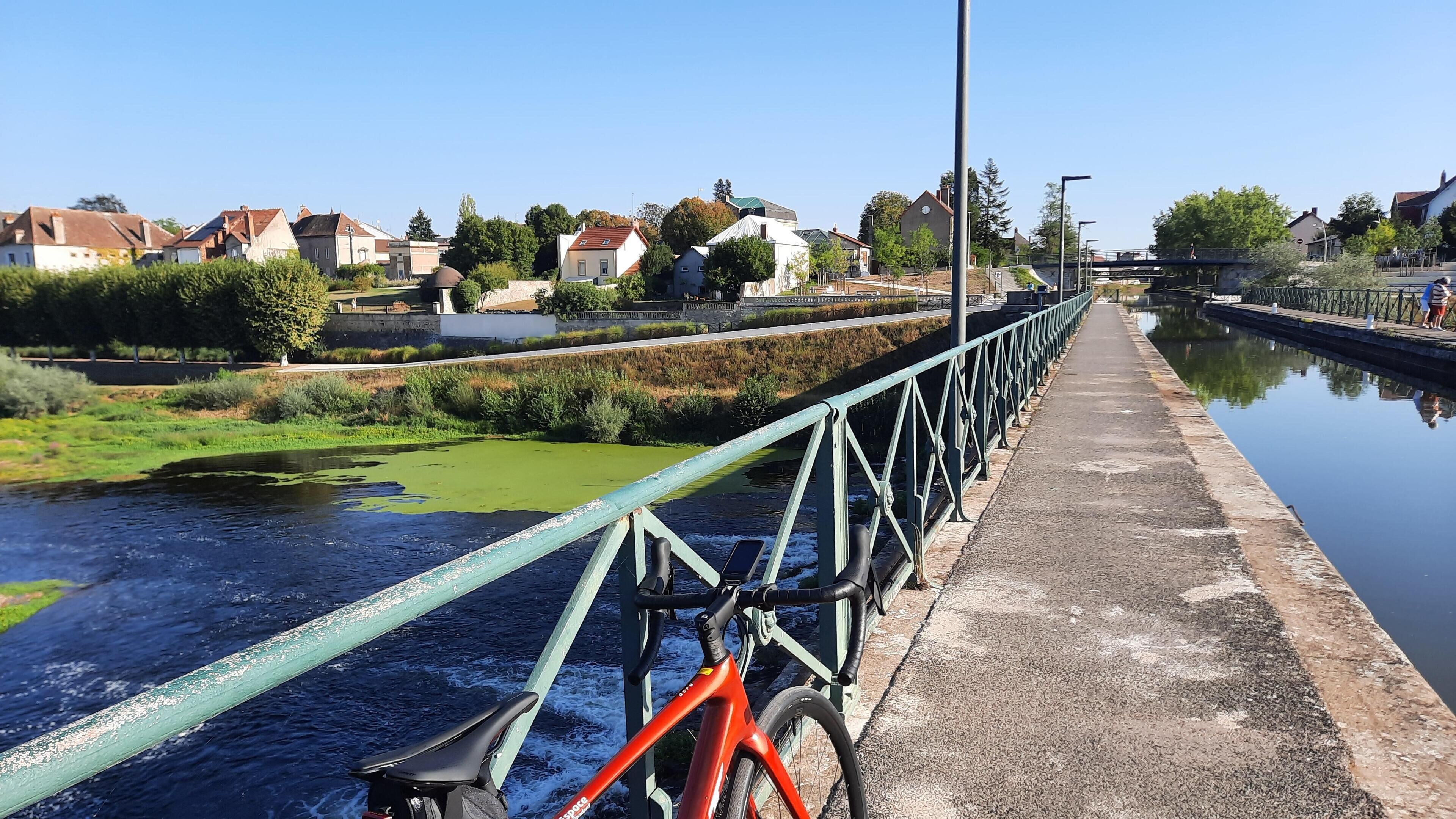A bridge over a canal with a bicycle parked on the side.