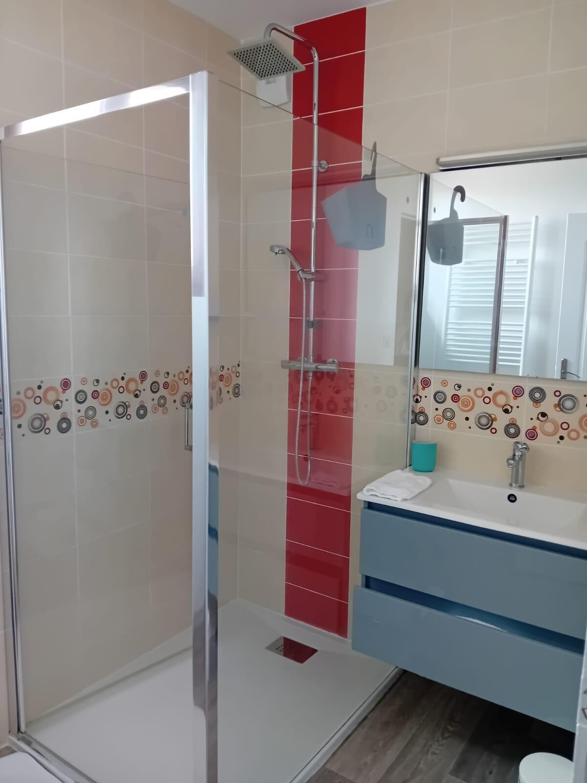 Une salle de bain moderne avec une douche à parois de verre, un lavabo avec un miroir et des carreaux décoratifs.
