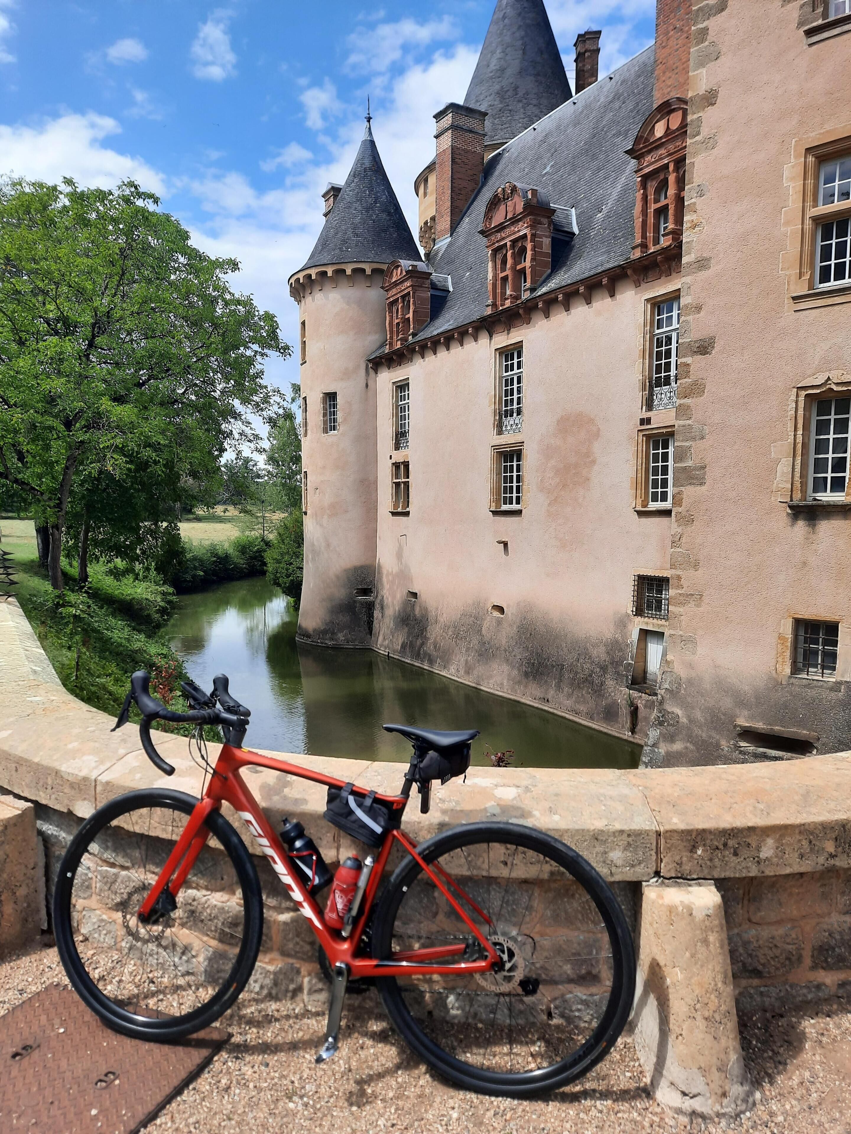 Een historisch gebouw met een gracht, een fiets en een heldere lucht.
