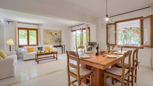 Uma sala ampla com uma mesa de jantar posta para quatro pessoas, um sofá e uma mesa de centro.