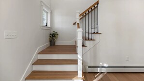 A staircase with wooden steps and white railings, a small window with a plant, and a thermostat on the wall. - Beautiful new home near Portland in quiet Cumberland (Cumberland)