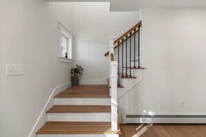 A staircase with wooden steps and white railings, a small window with a plant, and a thermostat on the wall. - Beautiful new home near Portland in quiet Cumberland (Cumberland)