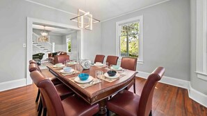 Uma sala de jantar com uma mesa de madeira posta para seis pessoas, rodeada por cadeiras de couro.