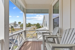 Eine überdachte Veranda mit weißen Geländern und zwei Adirondack-Stühlen.
