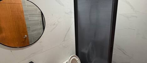 A bathroom with a toilet, sink, and a shower area.