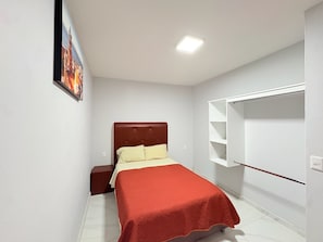 A bedroom with a bed, nightstand, and a white wardrobe.