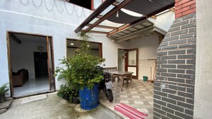 A courtyard with a blue pot, a motorcycle, a table, and a red mat. - Maria Antônia's Family Home (Paraty)