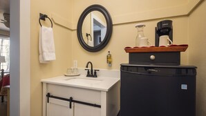 A bathroom with a sink, mirror, towel rack, and a coffee maker on a cabinet. - Sunflower Hill Inn (Moab)