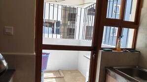 Une cuisine équipée d’un évier, d’une fenêtre et d’un balcon doté d’une rambarde en métal.