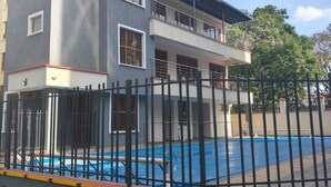 Un immeuble à plusieurs étages doté d’une piscine, d’une entrée sécurisée et surplombant un ciel dégagé.
