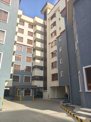 A multi-story residential building with balconies, a gated entrance, and a paved courtyard. - Central yet secluded oasis, Ideal for families  craving a stress‑free 
getaway. (Nakuru)