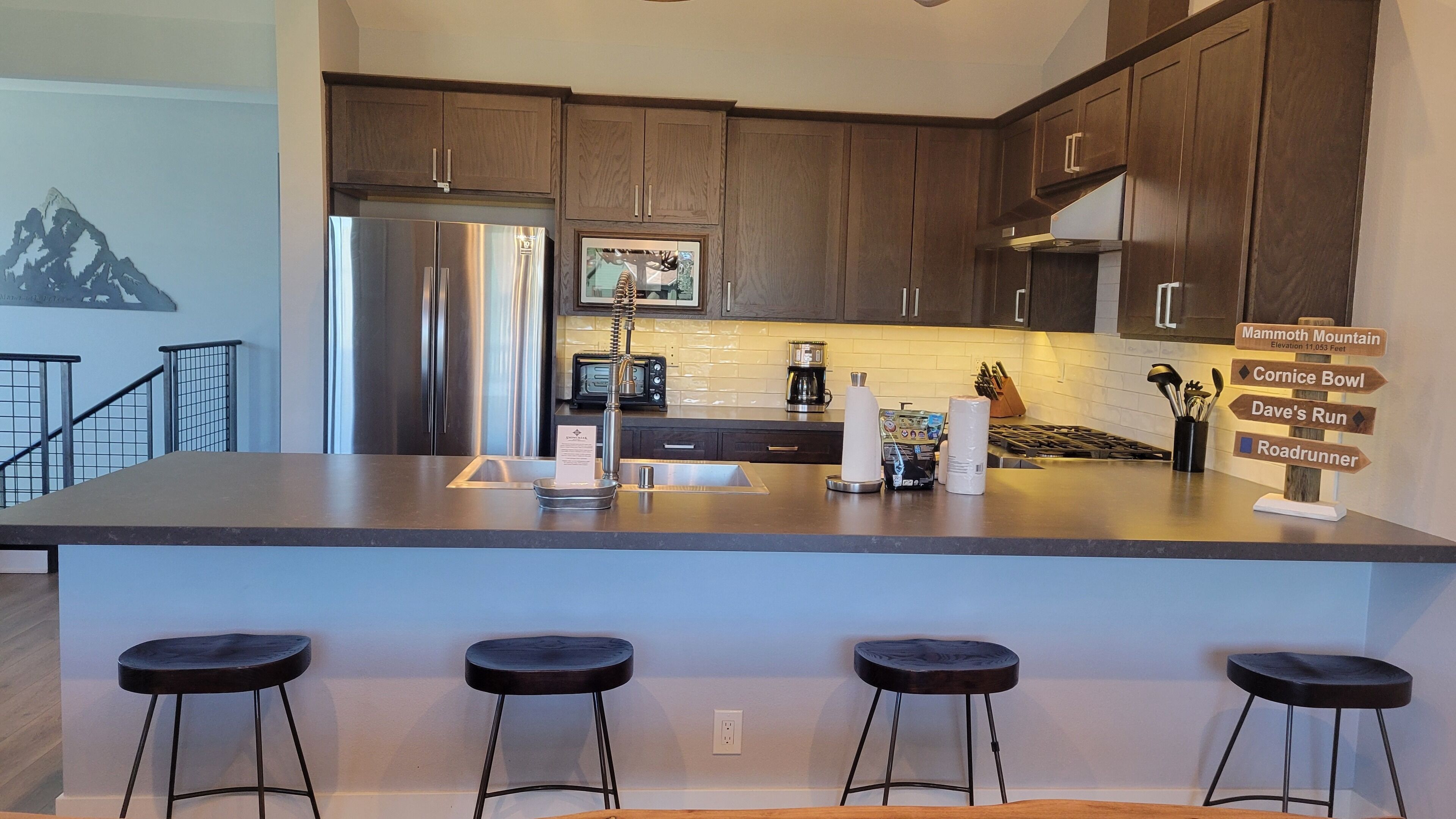Una cocina moderna con armarios de madera oscura, electrodomésticos de acero inoxidable y una isla central con taburetes de bar.