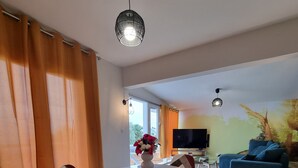 Ein modernes Wohnzimmer mit Essbereich, ausgestattet mit einem Glastisch, gestreiften Stühlen und einem großen Sofa.