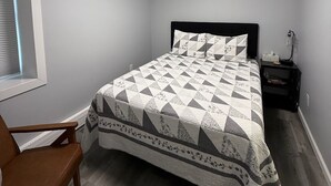 Une chambre à coucher avec un lit, une table de chevet, une chaise et une fenêtre avec des stores.