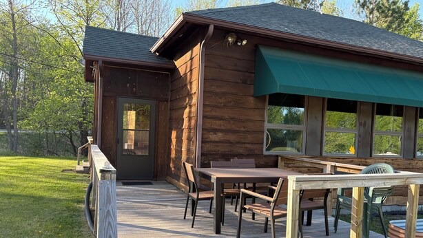 Une cabane en bois avec une terrasse, une table et des chaises.