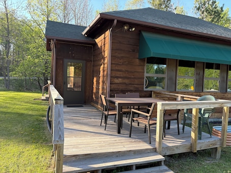 A wooden cabin with a deck, a table, and chairs.. 1 Br/1BA, full kitchen, AC, internet. Visit Voyageurs Nat'l Park!