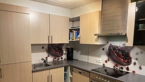Une cuisine moderne avec des meubles de couleur bois clair, un lave-vaisselle, un four et une machine à café.