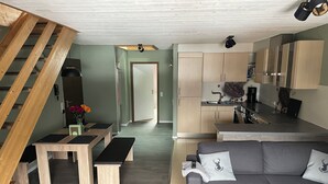 Un salon moderne avec un canapé gris, des bancs en bois et un escalier.