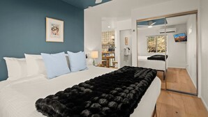Ein Schlafzimmer mit einem Bett, einer schwarzen Felldecke, einem Deckenventilator und einem Fernseher im angrenzenden Raum.