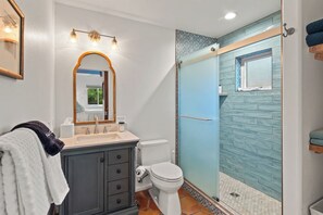 Ein Badezimmer mit Waschtisch, Toilette und Duschbereich mit blauer Wand.